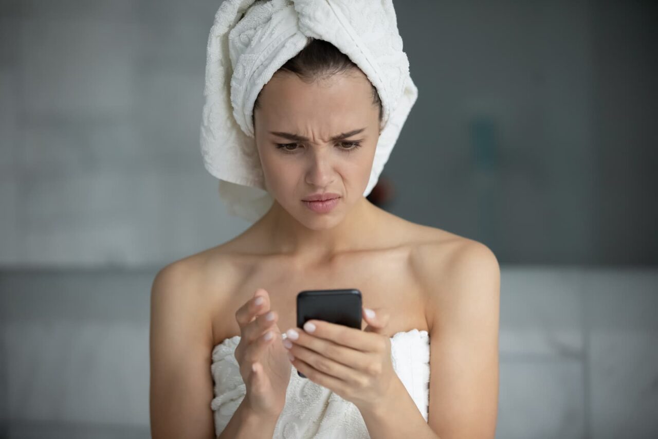 woman looks at her cell phone and ponders skin issues